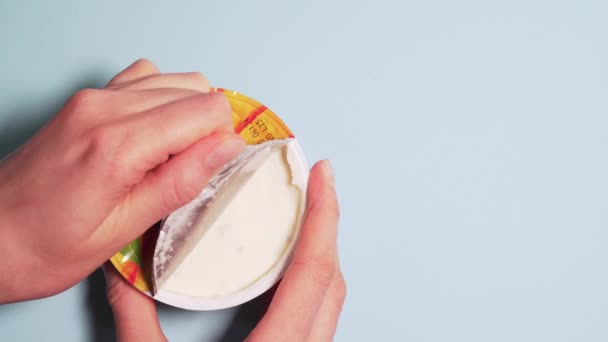 Свіжий органічний йогурт для правильного харчування. Жіночі руки повільно відкривають кришку йогурту, ізольовані на білому тлі — стокове відео