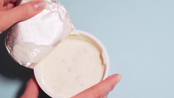 Crema di cagliata ecologica con nel latte di cocco. Le mani femminili strappano il coperchio da un barattolo di crema di cagliata. Copyspace per il testo — Video Stock