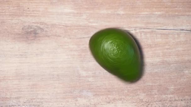 나무 탁자 위에서는 녹색의 이국적 인 아보카도가 돌고 있습니다. 채소 건강에 좋은 간식을 분리 함 — 비디오