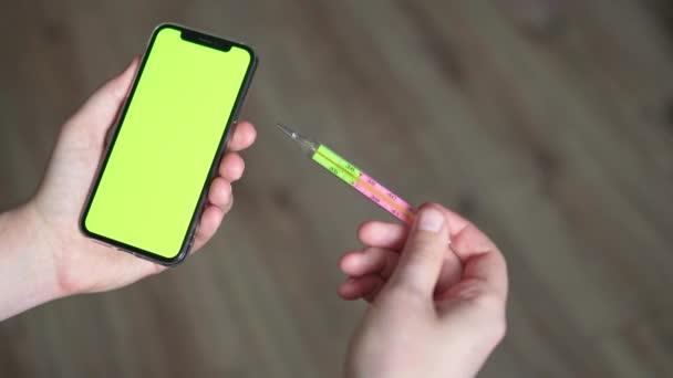 De man houdt een medische thermometer en een telefoon vast op het scherm van een chromakey. Het concept van coronavirus en pandemie. Meet uw lichaamstemperatuur thuis tijdens het griepseizoen en verkoudheid — Stockvideo