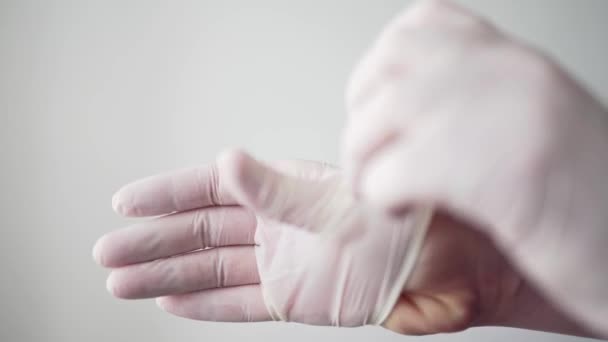 El médico se pone guantes protectores blancos en las manos. Un trabajador médico profesional. Coronavirus pandémico e infección — Vídeos de Stock