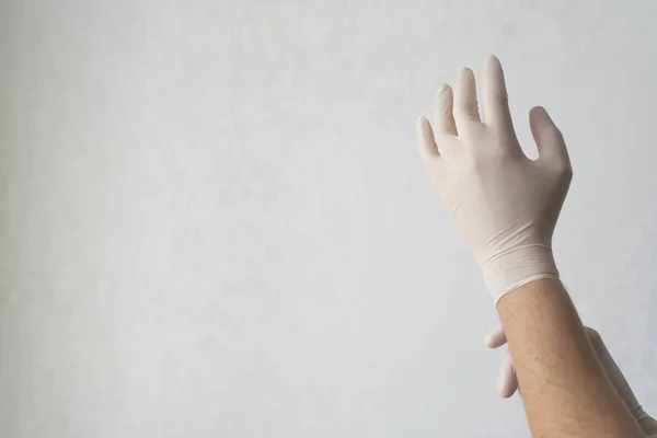 Врач надевает белые защитные перчатки на руки. Профессиональный медработник. Пандемия коронавируса и инфекции — стоковое фото