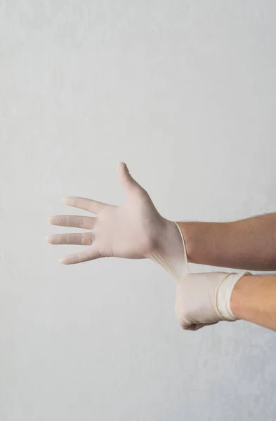 Концепция защиты от коронавируса. Человек надевает белые перчатки перед выходом на улицу во время эпидемии Ковид-19. Безопасная защита от вируса простуды и гриппа — стоковое фото