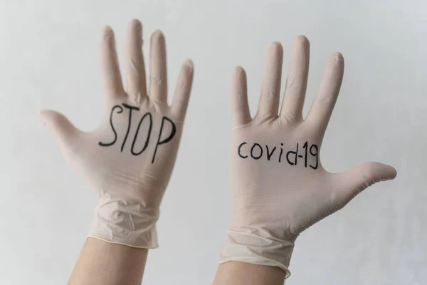Ferma il messaggio Covid-19 sui guanti medici bianchi. Un agente protettivo contro il coronavirus durante una pandemia — Foto Stock