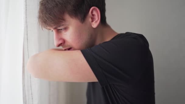 Junger Mann hustet in Arm oder Ellbogen, um die Ausbreitung des Virus zu verhindern. Statische Nahaufnahme — Stockvideo