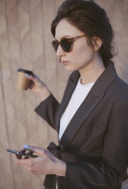 Parktaki brunchta habercilerle konuşan genç bir kadın. İş kadını kağıt bardaktan organik kahve içer.