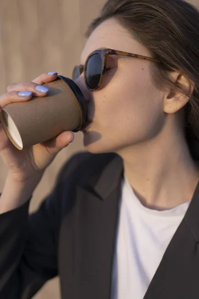 Деловая женщина любит отдыхать в парке. Крупный план женщины, делающей глоток кофе без лактозы из бумажной чашки — стоковое фото