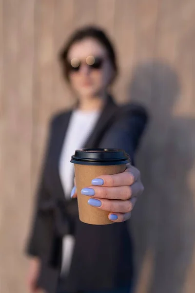 Бизнесмен протягивает черную эко-чашку кофе, обедает в парке — стоковое фото