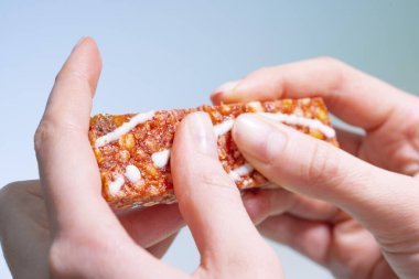 Sağlıklı bir aperatifi yakın plan çekiyoruz. Enerji çubuğu granola ellerinde