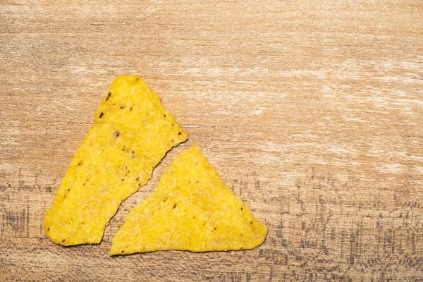 One yellow triangular nachos broken in half. Fast food and high-calorie food. Chips for snacking