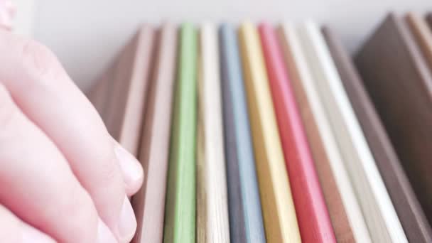 A man goes over colored furniture panels when choosing. Mans hands will choose the color of the sample. — Stock Video