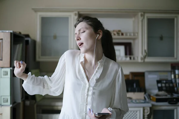 A female seller with headphones listens to music and dances at work in the store. A girl manager sings along to a song in the office