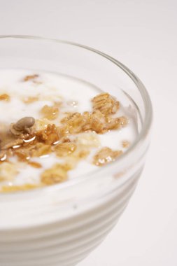 Sağlıklı bir kahvaltıyla yarım bardak. Beyaz arka planda granola ve ballı Yunan yoğurdu.