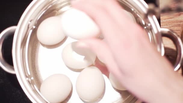 Rohe Hühnereier, die eine Frau zum Kochen ins Wasser gibt, der Blick von oben. Kochen aus nächster Nähe in der Küche — Stockvideo