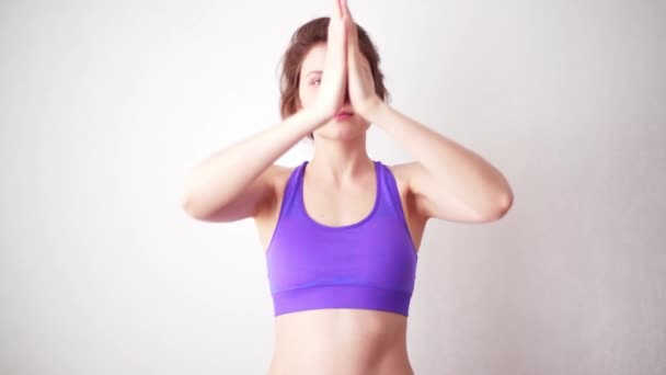 La mujer dobló los brazos en una asana y se está preparando para la meditación. Chica joven haciendo un ejercicio durante una emisión en línea — Vídeo de stock