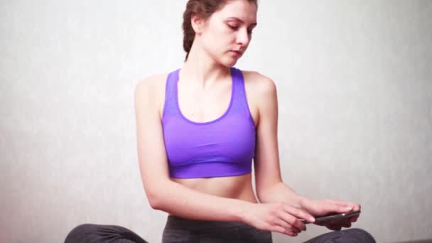 La donna accende la musica al telefono per la meditazione per rilassarsi e tuffarsi nello zen. Classe di quarantena Yoga Online — Video Stock