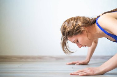 Dairesinde şınav çeken genç bir kadın. İnce ve sportif kız evde sporla meşgul. Sağlıklı yaşam tarzı, motivasyon ve refah kavramı
