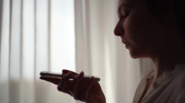 Özel asistanıyla telefonda konuşan bir kızın silueti. Telefonunda ses tanıma özelliği olan bir mesaj kaydet