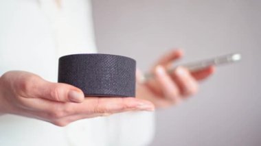 Senkronize telefon ve akıllı bir evi kontrol etmek için taşınabilir ses asistanı. Cep telefonundan taşınabilir sütuna kadar kızların ellerinin yakın plan görüntüsü