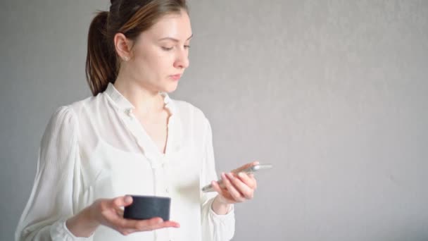 Una joven mujer conecta un asistente de voz en un dispositivo portátil a su teléfono sincronizándolos — Vídeos de Stock