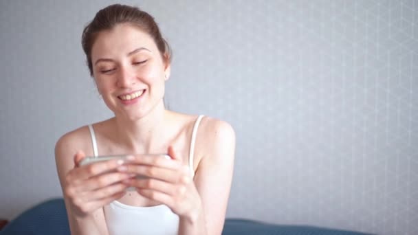 Diffusion de films au téléphone. Une jeune femme heureuse regarde un film sur l'écran de son smartphone. Réaction positive d'une personne en regardant la vidéo — Video