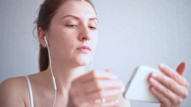 Transmisión de películas online. La chica conecta sus auriculares a un teléfono móvil y enciende la película — Vídeo de stock