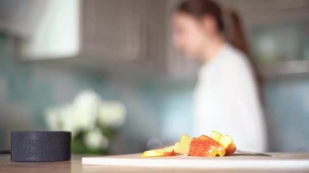 Cozinhar com as funções de uma casa inteligente. Uma jovem mulher usa um assistente de voz em sua cozinha close-up — Vídeo de Stock