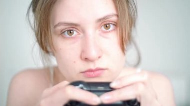 Oyun bağımlılığı. Bir kadın oyuncu, TV karşısında konsol jostik oynarken yakın plan bir oyun bağımlılığıyla karşı karşıya kalır.