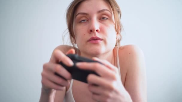 Μια νεαρή γυναίκα χιλιετή παίζει με ενθουσιασμό ένα παιχνίδι χρησιμοποιώντας το χειριστήριο από την κονσόλα. Ζωηρά συναισθήματα από το φόβο στα πρόσωπα των κοριτσιών από το παιχνίδι σε απευθείας σύνδεση — Αρχείο Βίντεο