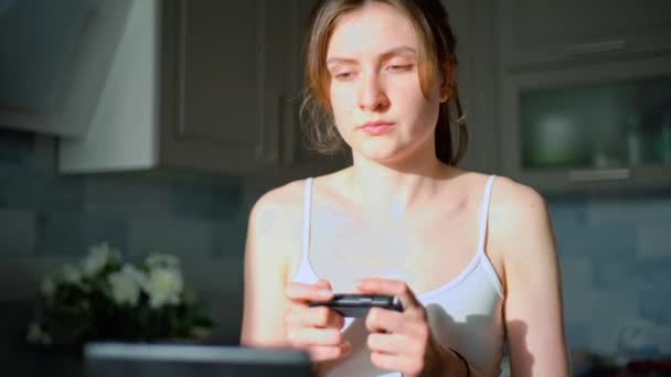 Uma jovem joga videogames em um joystick. Um console de jogo portátil. Dependência em jogos de azar — Vídeo de Stock