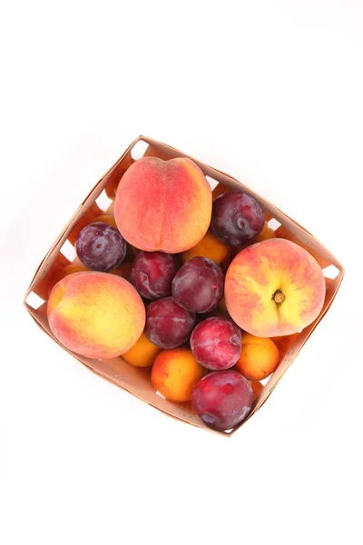 Pfirsiche, Aprikosen und Pflaumen in einem Korb isoliert auf weißem Hintergrund — Stockfoto
