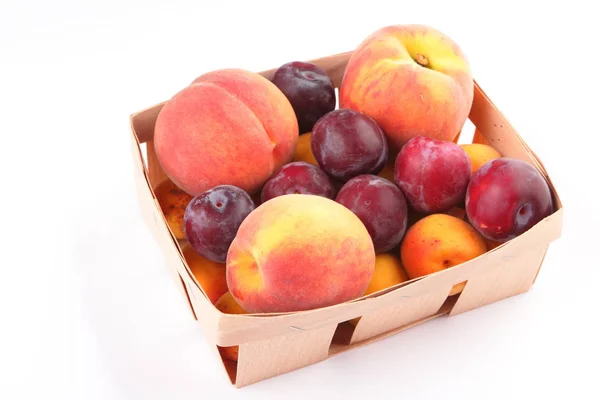 Pfirsiche, Aprikosen und Pflaumen in einem Korb isoliert auf weißem Hintergrund — Stockfoto
