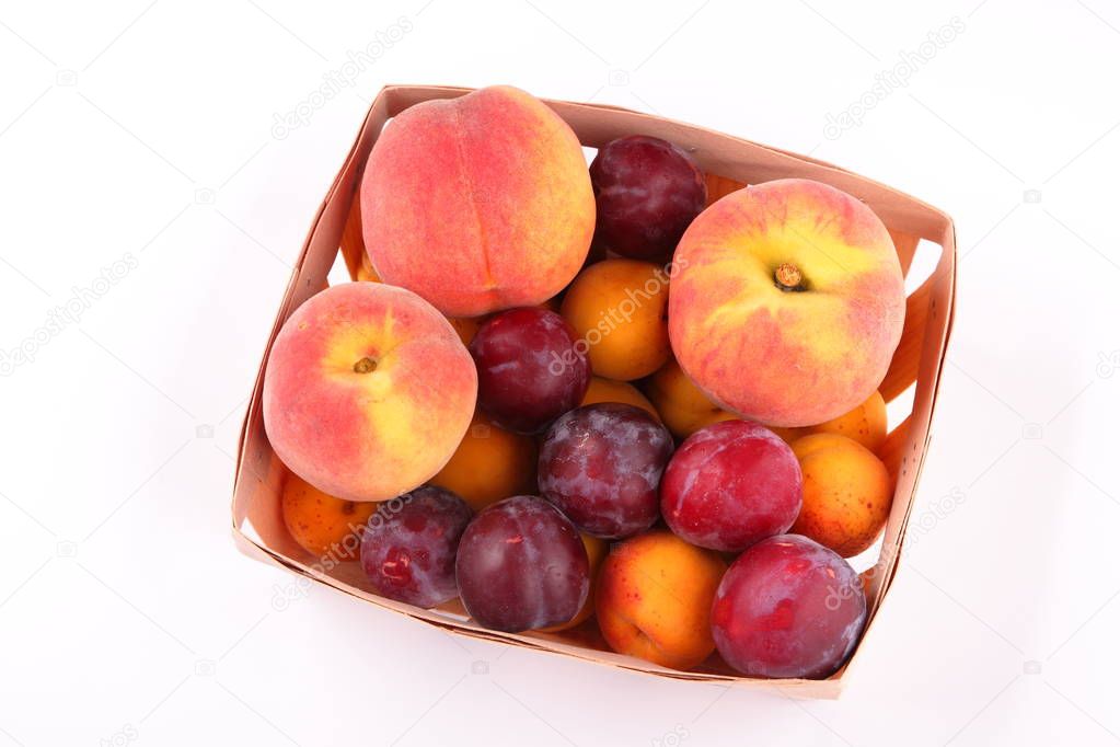 Peaches, apricots and plums in a basket isolated on white background