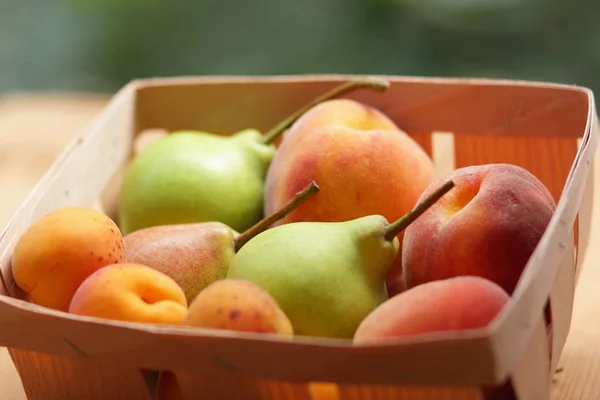Birnen und Pfirsiche in einem Holzkorb — Stockfoto