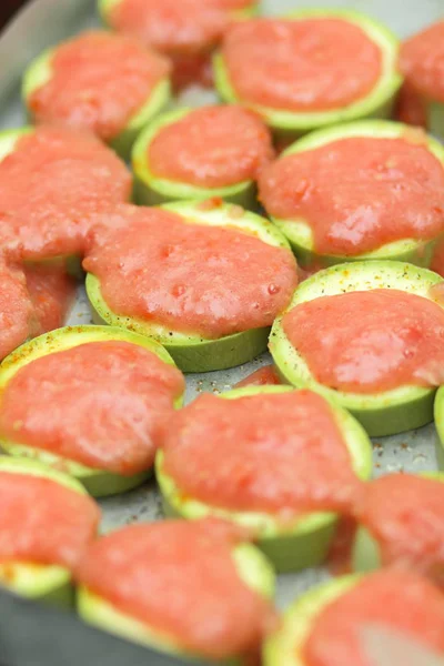 Sliced zucchini topped with tomato sauce before baking — Stock Photo, Image