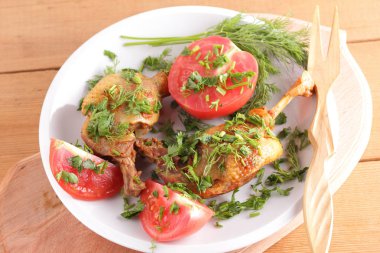 Kızarmış ördek bacaklar domates ve otlar ile ahşap çatal bıçak takımı