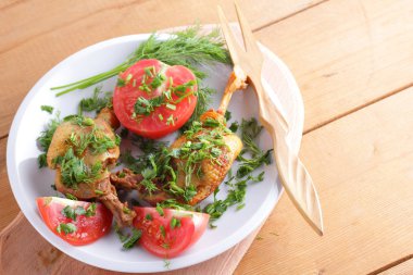 Kızarmış ördek bacaklar domates ve otlar ile ahşap çatal bıçak takımı