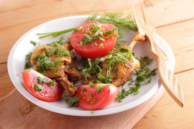 Kızarmış ördek bacaklar domates ve otlar ile ahşap çatal bıçak takımı