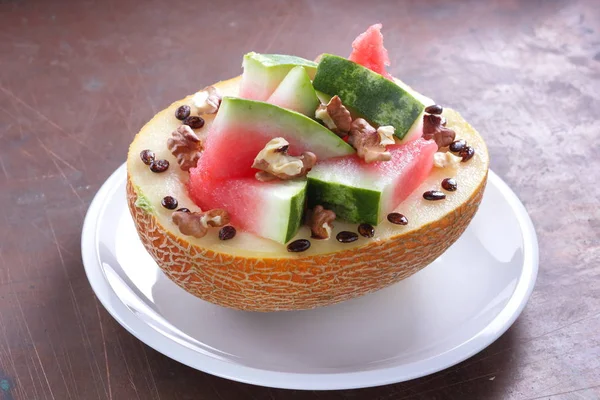 Beyaz bir plaka üzerinde ceviz serpilir karpuz, kavun dolması