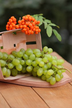 Bir avuç üzüm ve ahşap sepet içinde olgunlaşmış üvez