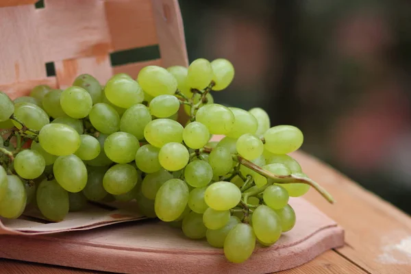 Um monte de uvas verdes em uma cesta de madeira para um designer — Fotografia de Stock