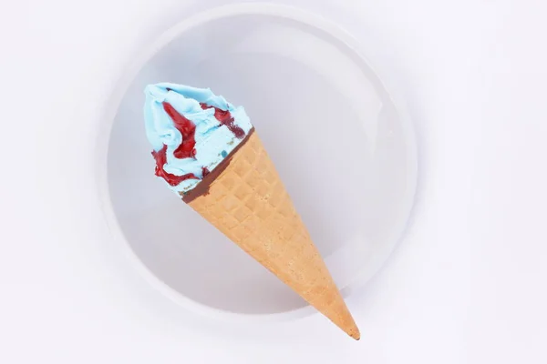 Sorvete em uma xícara de waffle com recheio azul e engarrafamento vermelho em uma chapa branca do desenhista — Fotografia de Stock