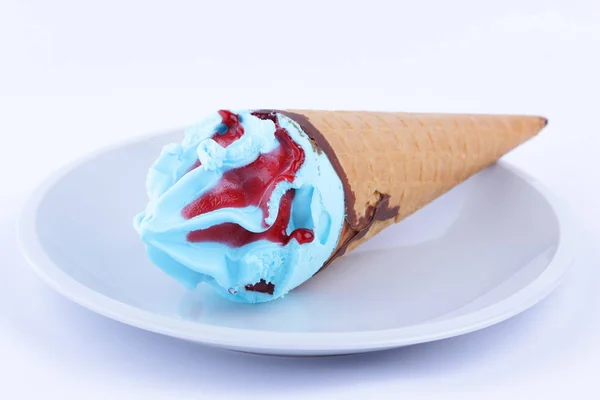 Мороженое в вафельной чашке с голубой начинкой и красным джемом на белой тарелке для дизайнера — стоковое фото