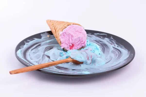 Eis im Waffelbecher mit bunter Füllung und roter Marmelade auf schwarzem Teller mit Holzlöffel für die Designerin — Stockfoto