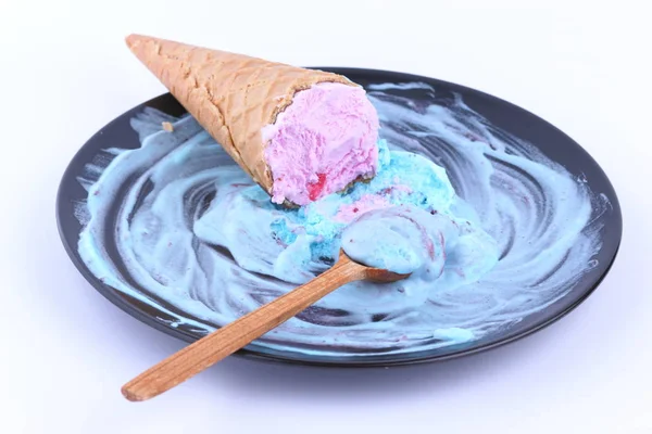 Helado en una taza de gofres con un relleno multicolor y mermelada roja en un plato negro con una cuchara de madera para el diseñador — Foto de Stock