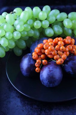 Yeşil üzüm, mavi Erik ve turuncu üvez meyveleri retro tarzı tasarımcısında için siyah bir plaka üzerinde