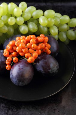 Yeşil üzüm, mavi Erik ve turuncu üvez meyveleri retro tarzı tasarımcısında için siyah bir plaka üzerinde