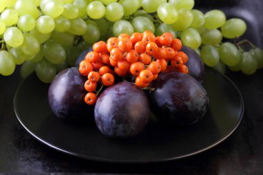 Yeşil üzüm, mavi Erik ve turuncu üvez meyveleri retro tarzı tasarımcısında için siyah bir plaka üzerinde