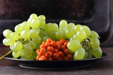 Yeşil üzüm, mavi Erik ve turuncu üvez meyveleri retro tarzı tasarımcısında için siyah bir plaka üzerinde