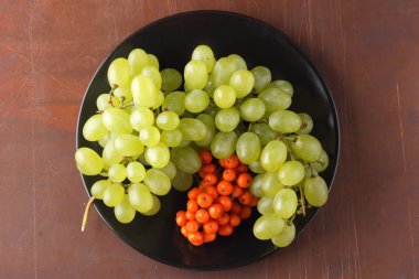 Yeşil üzüm, mavi Erik ve turuncu üvez meyveleri retro tarzı tasarımcısında için siyah bir plaka üzerinde